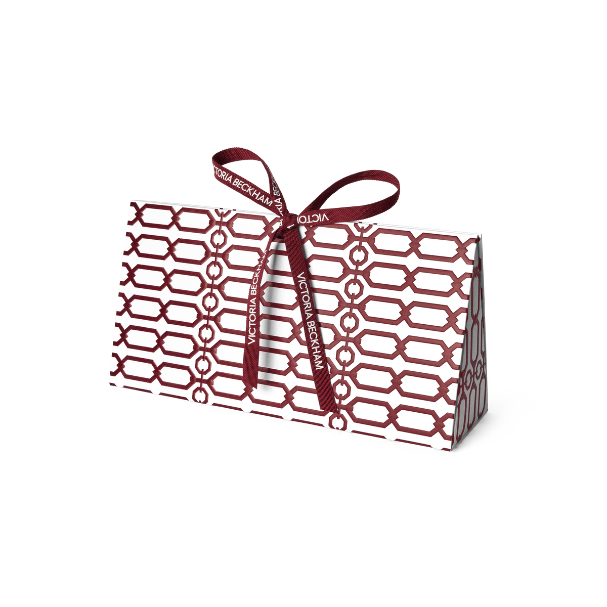 Burgundy trellis-print gift box tied with a branded ribbon bow on grey — Victoria Beckham Beauty holiday gift packaging.