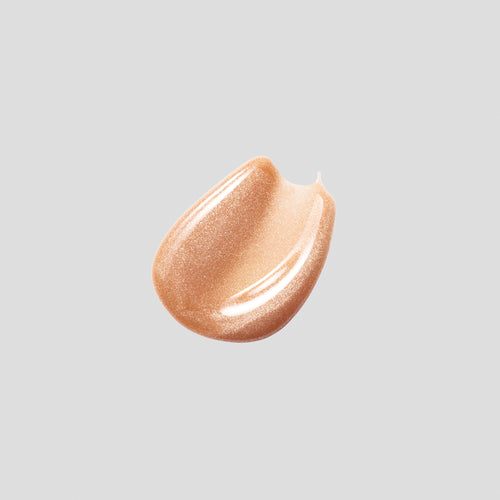 Glossy swatch of Posh Gloss Martini on grey backdrop — Victoria Beckham Beauty's champagne gold shimmer lip gloss.